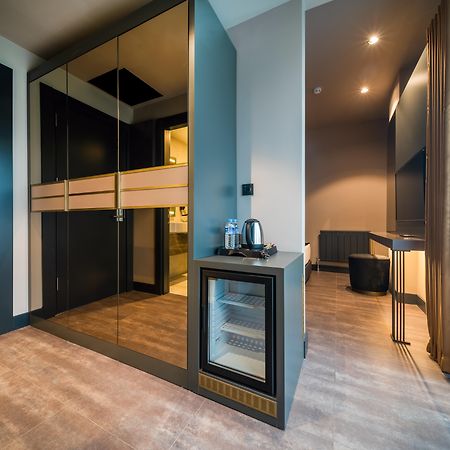 Menalo Hotel Premium Istanbul Airport Zewnętrze zdjęcie The photo shows a modern interior space that appears to be part of a hotel room or a high-end apartment. On one side, there is a set of sleek, dark wardrobes with mirrored doors. Next to the wardrobes, there is a small bar area or mini-fridge with a 