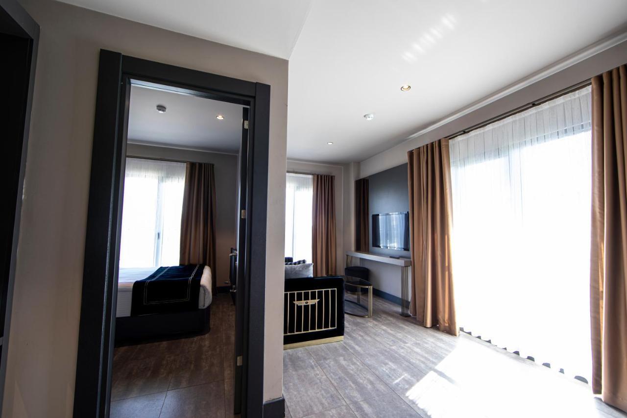 Menalo Hotel Premium Istanbul Airport Zewnętrze zdjęcie The photo shows an interior space, likely a hotel room or suite. On the left, there is a doorway leading to another area, and across from it, large windows with light-colored curtains allow natural light to enter the room. 

The room features a cozy 