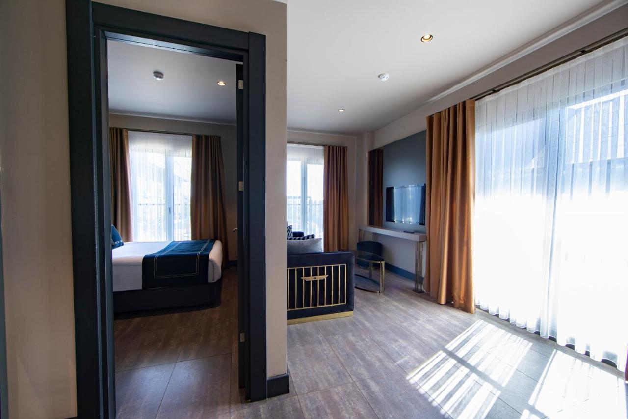 Menalo Hotel Premium Istanbul Airport Zewnętrze zdjęcie The photo shows a modern hotel room set up. In the foreground, there is an entrance leading to the room, with a view of a second room through an open door. The interior features large windows with sheer curtains allowing natural light to fill the spa